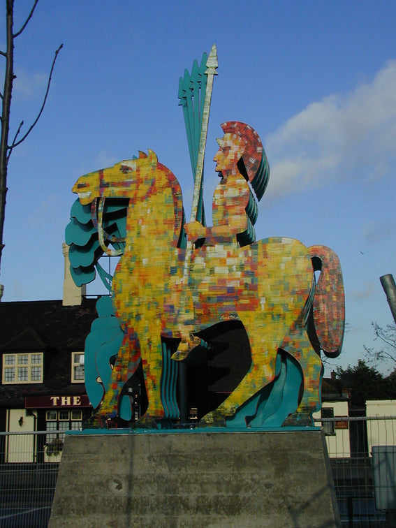 David Gerstein's Roman Warrior sculpture sits atop a concrete block. It is painted in yellow and red.