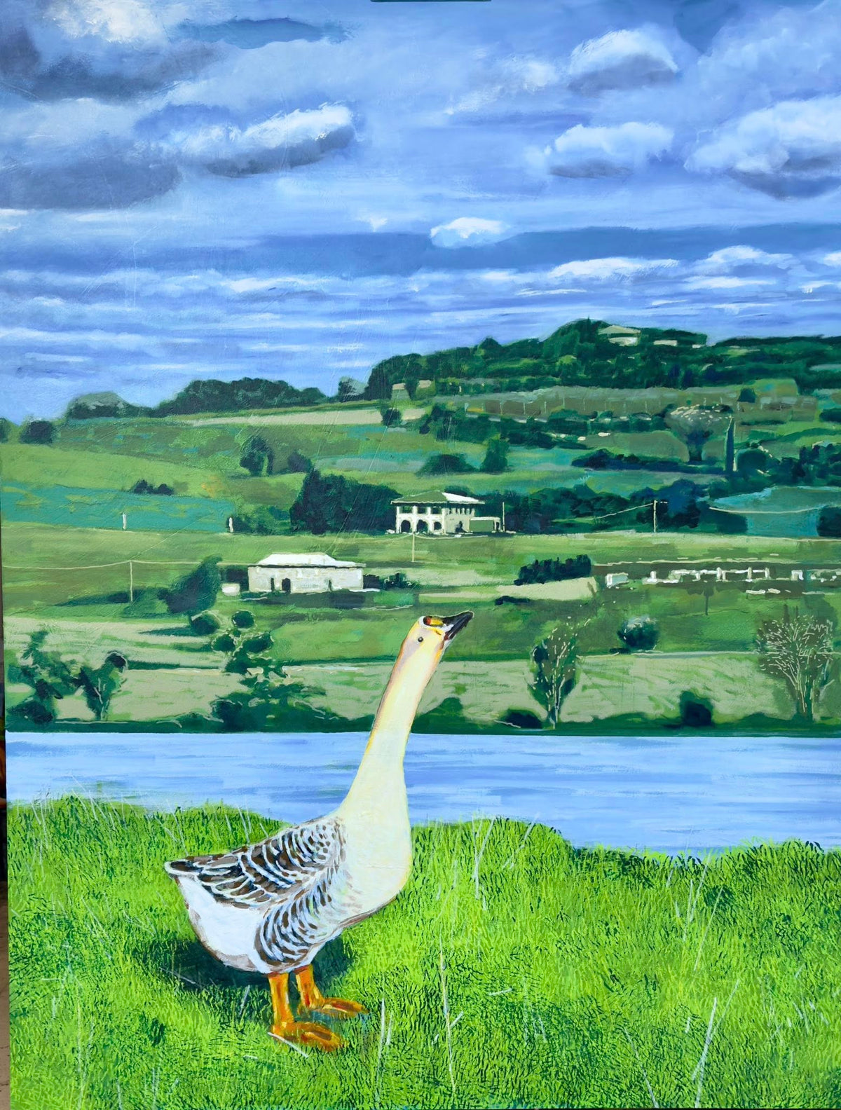 Goose standing on grass near a lake with a scenic landscape in the background