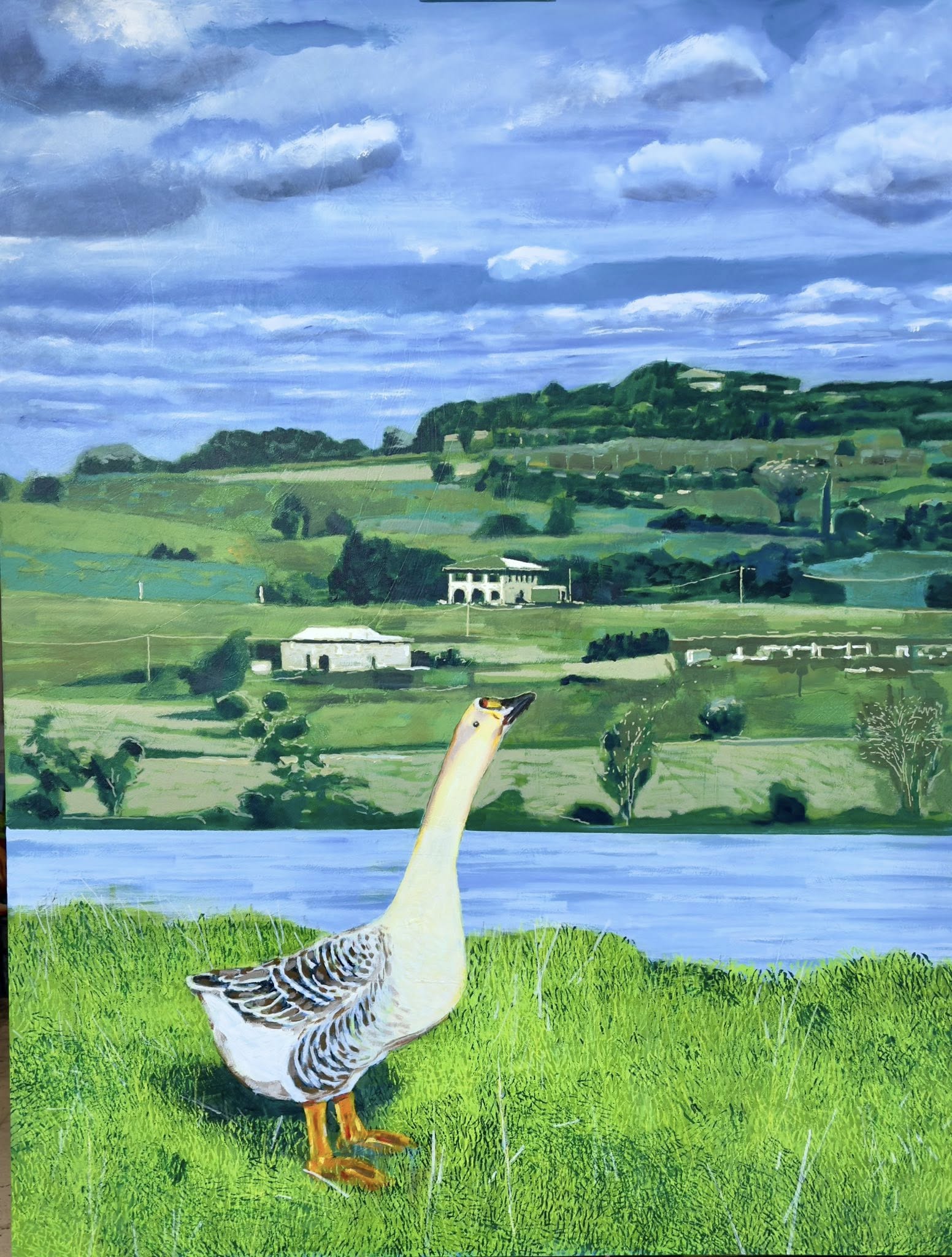 Goose standing on grass near a lake with a scenic landscape in the background